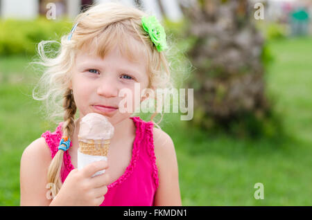 Little child blond girl licking lollipop outside in garden, portrait ...