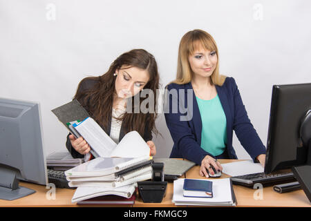 Female colleagues in the office, one works with paper documents, the second computer with electronic Stock Photo