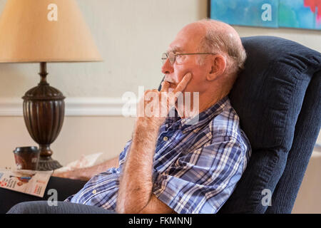 An elderly Caucasian man, sitting in a recliner stares into space while suffering from dementia and depression. USA. Stock Photo