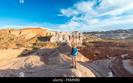 Tourist, hiker at the Fire Wave Sandstone Formation, behind Sleeping Lizard rock formation, Valley of Fire State Park, Nevada Stock Photo