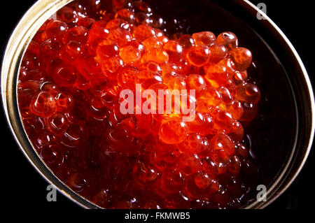 Red caviar in a can on a black background Stock Photo