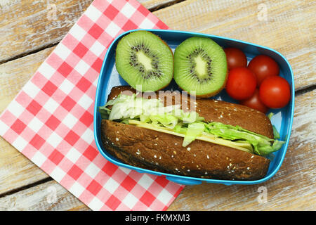 Healthy lunch consisting of brown cheese and lettuce roll, cherry tomatoes and kiwi fruit Stock Photo