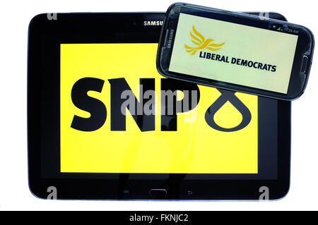 The SNP and Liberal Democrat logos displayed on the screens of a tablet and a smartphone against a white background. Stock Photo