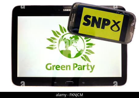 The SNP and Green Party logos displayed on the screens of a tablet and a smartphone against a white background. Stock Photo