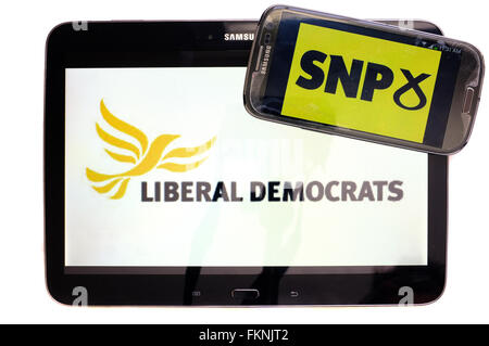 The Liberal Democrat and SNP logos displayed on the screens of a tablet and a smartphone against a white background. Stock Photo