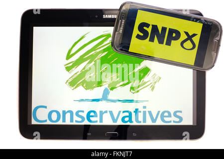 The Conservative and SNP logos displayed on the screens of a tablet and a smartphone against a white background. Stock Photo