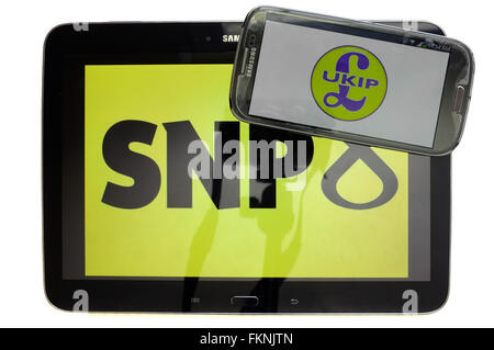 The SNP and UKIP logos displayed on the screens of a tablet and a smartphone against a white background. Stock Photo