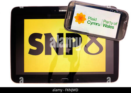 The SNP and Plaid Cymru logos displayed on the screens of a tablet and a smartphone against a white background. Stock Photo