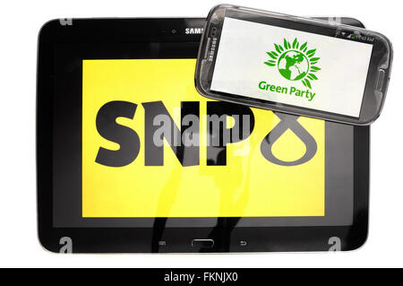 The SNP and Green Party logos displayed on the screens of a tablet and a smartphone against a white background. Stock Photo