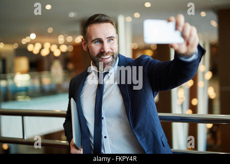 Businessman in black suit using a mobile phone for a video call with partners Stock Photo