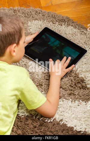 Boy lying on floor and using digital tablet Stock Photo