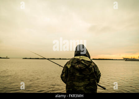 Caucasian man fishing in remote lake Stock Photo