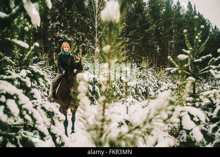 Caucasian woman riding horse in snowy forest Stock Photo