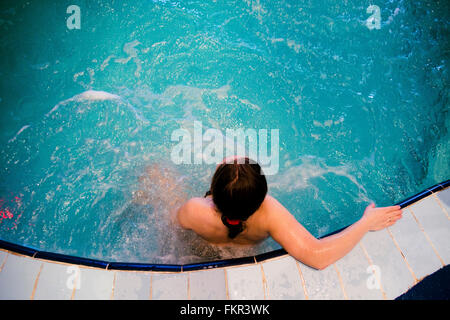 Caucasian woman sitting in swimming pool Stock Photo