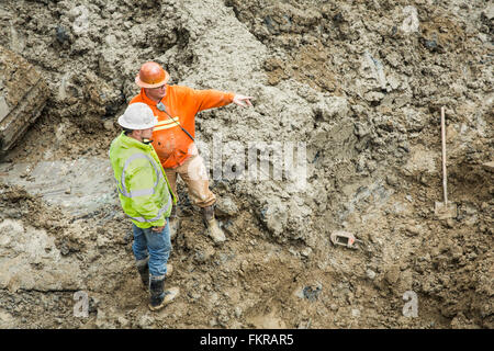 Caucasian workers talking at construction site Stock Photo