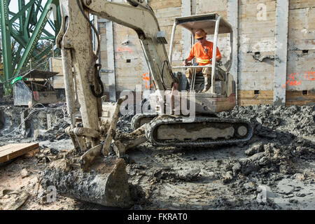Caucasian worker using digger at construction site Stock Photo