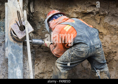 Caucasian worker drilling at construction site Stock Photo