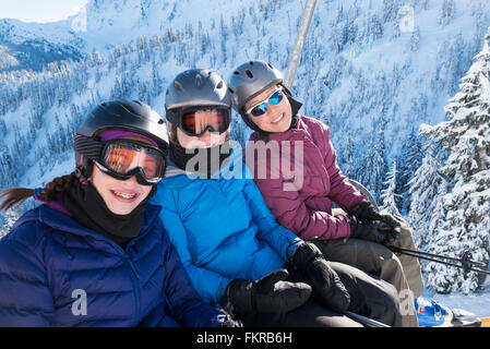 Mother and daughters riding ski lift Stock Photo