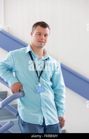 Caucasian man with Down Syndrome wearing badge on stairs Stock Photo