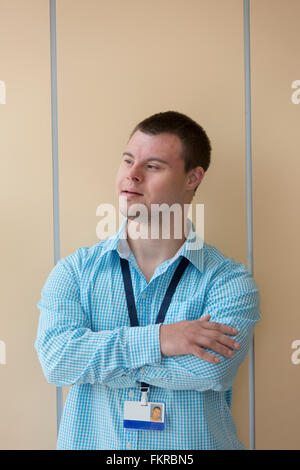 Caucasian man with Down Syndrome wearing badge at wall Stock Photo