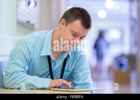 Caucasian man with Down Syndrome using digital tablet in hospital Stock Photo