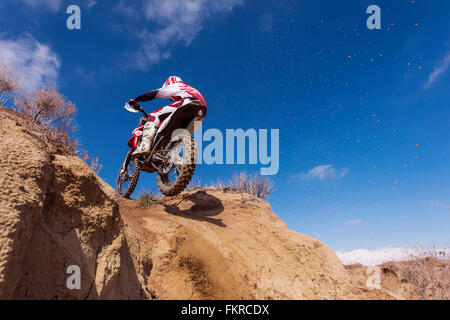 Motorcyclist riding dirt bike on hillside Stock Photo