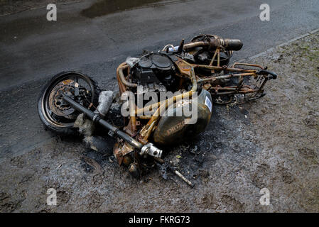 An abandoned and burntout motorcycle on the cycle track in Leith, Edinburgh, Scotland, UK. Stock Photo