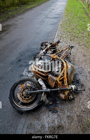 An abandoned and burntout motorcycle on the cycle track in Leith, Edinburgh, Scotland, UK. Stock Photo