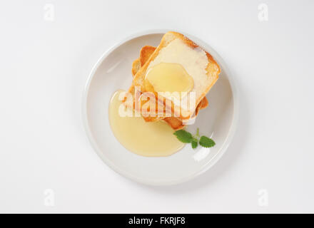 plate of freshly made toasts with butter and honey on white background Stock Photo
