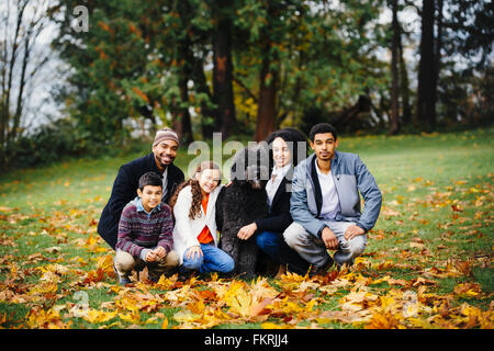 Family and dog smiling in park Stock Photo