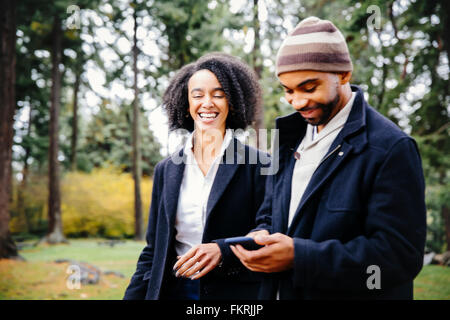 Couple using cell phone in park Stock Photo