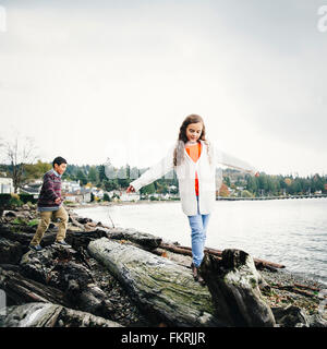 Mixed race children climbing on logs at lake Stock Photo