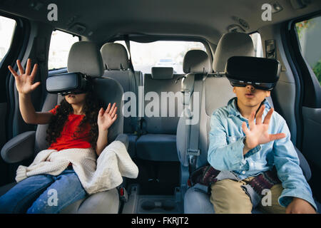 Mixed race children using virtual reality goggles in car