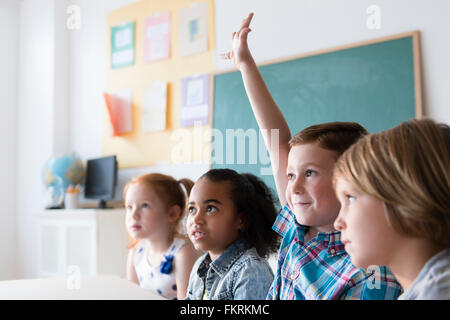 Student raising hand in classroom Stock Photo