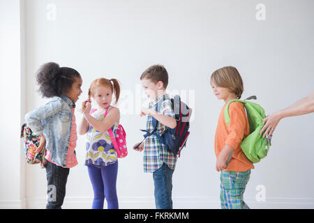 Students wearing backpacks in classroom Stock Photo