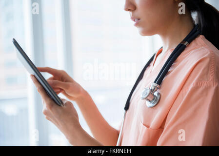 Mixed race nurse using digital tablet Stock Photo