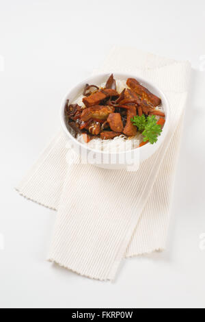 bowl of roasted meat, ear mushrooms and rice noodles on white place mat Stock Photo