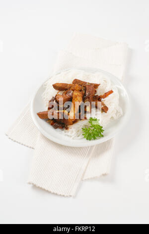 plate of roasted meat, ear mushrooms and rice noodles on white place mat Stock Photo