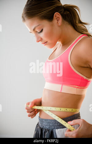 Mixed race woman measuring her waist Stock Photo