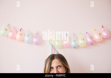 Caucasian woman wearing party hat at birthday Stock Photo