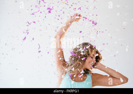 Mixed race woman playing in confetti Stock Photo