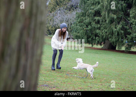 Japanese woman playing with dog in park Stock Photo