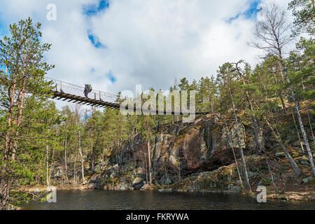 Trekker crossing a hanging bridge in Repovesi National Park, Finland. Stock Photo