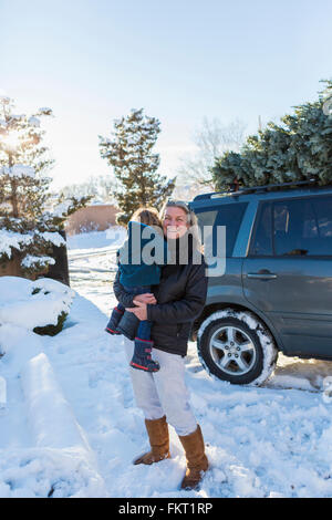 Caucasian mother holding son in snow Stock Photo