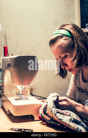 Caucasian woman using sewing machine Stock Photo