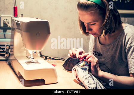 Caucasian woman using sewing machine Stock Photo