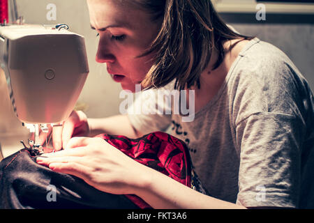 Caucasian woman using sewing machine Stock Photo