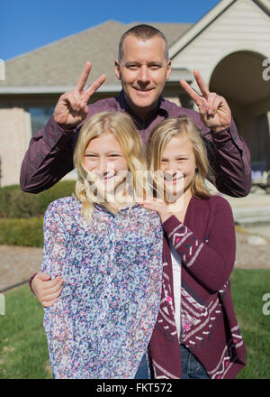 Caucasian father and daughters smiling in yard Stock Photo