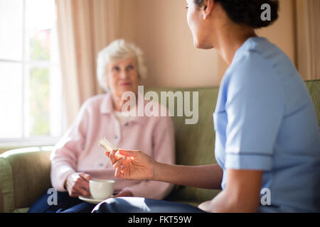 Nurse and patient drinking tea on sofa Stock Photo