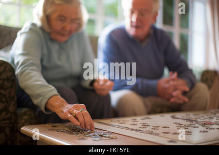 Older couple on sofa solving jigsaw puzzle Stock Photo